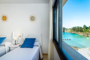 a bedroom with a view of the water from a window at Apartamentos Punta Lucero en Portonovo in Portonovo