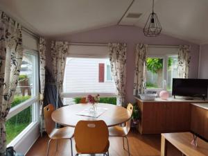 a dining room with a table and two windows at Chez Sab in Dannes