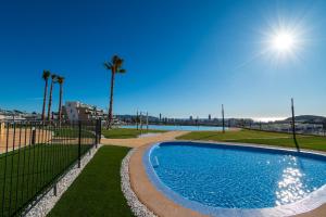 une piscine avec une clôture et des palmiers dans l'établissement BENIDORM Amber Stay, à Finestrat