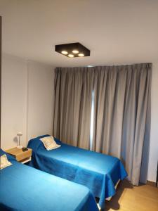 a bedroom with two blue beds and a window at Duplex a estrenar!! Zona Parque in Necochea
