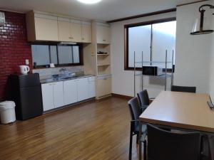 a kitchen with white cabinets and a table and chairs at Hostel 鶴々 in Shingū