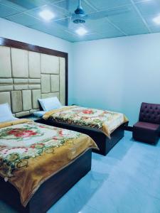 a room with two beds and a chair in it at Royal Residency Guest House Karachi in Karachi +24 photos