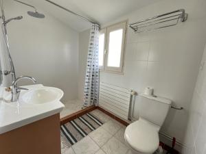 a bathroom with a toilet and a sink and a window at Les Saules in Saint-Gilles-Croix-de-Vie