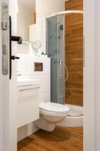 a bathroom with a toilet and a glass shower at Flamingo - Nadmorski Apartament Przy Lesie - Love & Family Apartments in Sopot