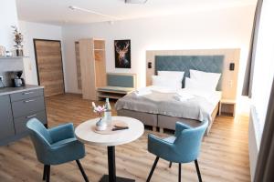 a hotel room with a bed and a table and chairs at HarzHold - Apartmenthotel in Osterode
