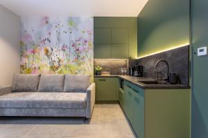 eine Küche mit grünen Schränken und einem Sofa in einem Zimmer in der Unterkunft Apart-Invest Gimnazjalna 3 in Szklarska Poręba