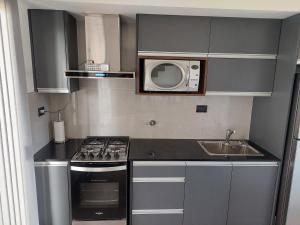a small kitchen with a stove and a microwave at Duplex a estrenar!! Zona Parque in Necochea