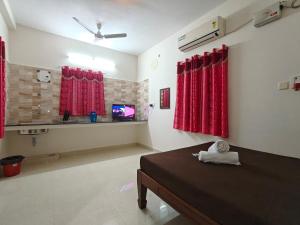 Habitación con cortinas rojas, cama y TV. en Stellar Stays, en Auroville
