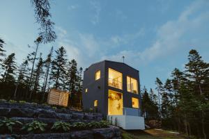 a small black house with its lights on at Chalet BLOK in Lac-Beauport