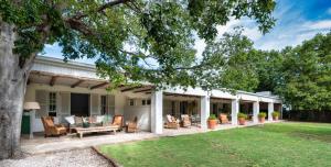 格拉夫-里内特Langhuis Guesthouse的一个带椅子和一棵树的房子的门廊