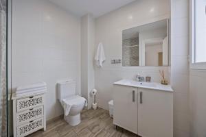 a white bathroom with a toilet and a sink at Apartamentos Benidorm Chorrol in Benidorm +64 photos