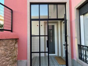 a door to a pink building with glass at Coração do Castelo AL in Castelo Branco