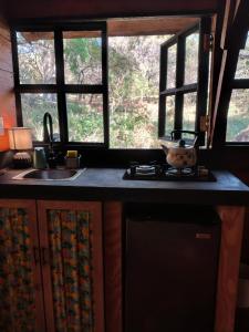 a kitchen with a sink and two windows at Cabaña de madera privada y romántica in Tepoztlán