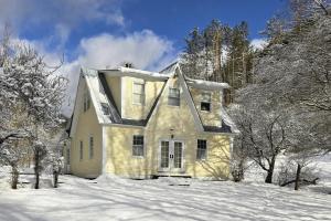 a house in the snow with snow covered trees at The Daydream Cottage in Woodstock