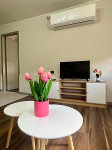 una sala de estar con una mesa blanca y flores rosas en Departamento Álamo, en Puerto Montt