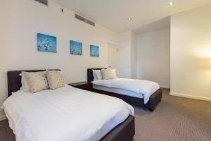 a bedroom with two beds and two paintings on the wall at Gallery Serviced Apartments in Fremantle +47 photos