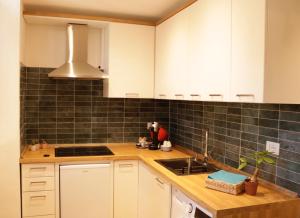 eine Küche mit weißen Schränken und schwarzen Fliesen an der Wand in der Unterkunft Domus Tepula II in Rom