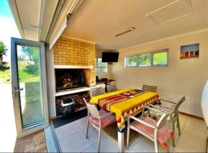 a dining room with a table and chairs and a fireplace at Nou wat nou in Pearly Beach