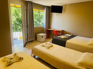 a hotel room with two beds and a desk and window at El Caminito in São Borja