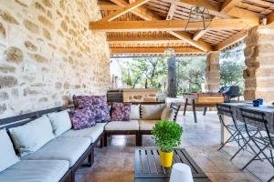 eine Terrasse mit Sofas und einem Tisch in einer Steinwand in der Unterkunft Bastide Aubignan in Aubignan