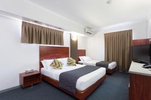 a hotel room with two beds and a flat screen tv at Rocklea International Motel in Brisbane