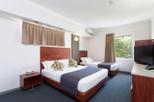 a hotel room with two beds and a flat screen tv at Rocklea International Motel in Brisbane