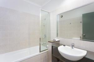 a bathroom with a sink and a shower and a mirror at Rocklea International Motel in Brisbane