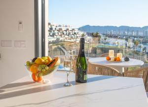 - une bouteille de vin et un bol de fruits sur une table dans l'établissement BENIDORM Amber Stay, à Finestrat