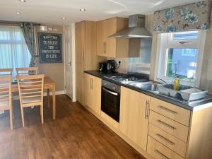 a kitchen with wooden cabinets and a sink and a table at Red Deer Village Holiday Park - 2 Bedroom, Self-Catering Chalet in Steps