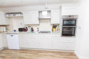 a white kitchen with white cabinets and a sink at Honeysuckle Cottage Newton Ferrers in Newton Ferrers