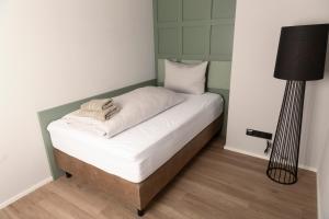 un letto con lenzuola bianche e una lampada in una stanza di STORK'S NEST a Schrobenhausen