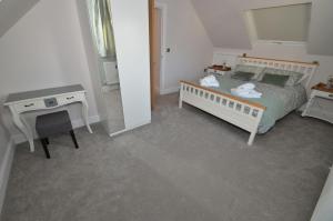a bedroom with a bed and a table and a desk at Grove Lodge - A Somerset Retreat in Radstock