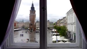 a window view of a city square with a clock tower at Residence B&B La Fontaine Aparthotel in Krakow
