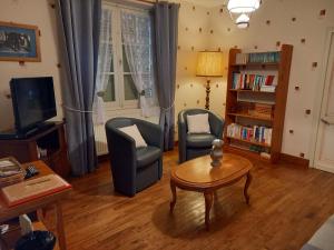 sala de estar con 2 sillas, mesa y TV en Gîte de Bazeille, en Saint-Avit-Sénieur