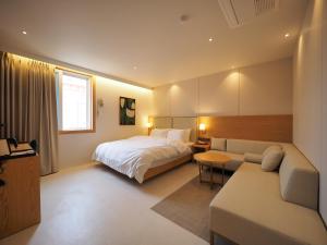 una camera da letto con un letto e un divano di Daisy hotel a Tongyeong Altre 49 foto