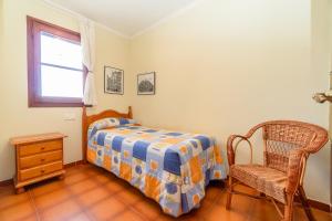 a bedroom with a bed and a chair and a window at Acogedora casa cerca de la playa in Torredembarra