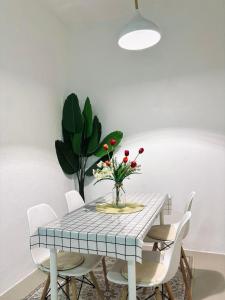 a dining room table with white chairs and a vase of flowers at JRC Homestay Kerteh in Kemaman +3 photos
