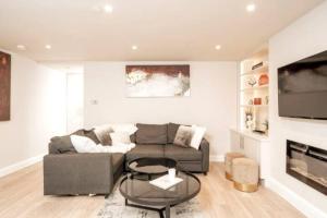 a living room with a couch and a tv at Niru Experience Jewel Of Ifield Road in London