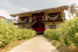a building with a thatch roof and a pathway at Garden House - Ilha do Guajiru in Itarema