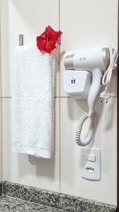 secador de pelo blanco en la pared con toalla en Kaapalua, en Porto de Galinhas