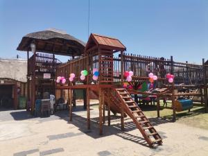 a playground with a wooden play structure with a slide at Jamrock Lodge in Winterveld