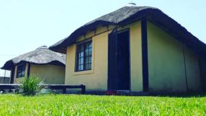 a small hut with a grass roof on a field at Jamrock Lodge in Winterveld