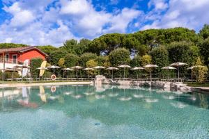 a pool of water with umbrellas in front of a building at Club del Sole Viareggio Family Collection in Torre del Lago Puccini