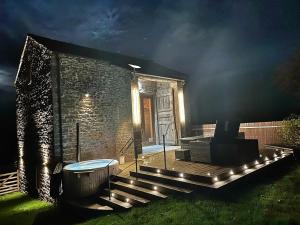una casa con vasca idromassaggio nel cortile di notte di Owls Nook Barn, Luxury Barn with Hot Tub & Sauna a Sandford