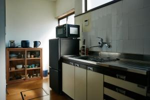 a kitchen with a black refrigerator and a microwave at ふもとの山小屋 ネイバーズ Neighbors - Alpine Base Inn in Matsumoto