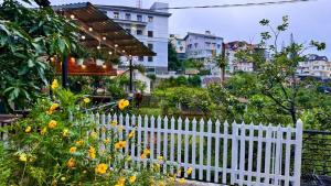 a white picket fence in a garden with flowers at Nhà của Sóc in Da Lat