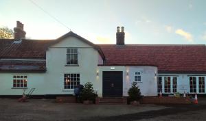 a white house with a black door at Trowel and Hammer, Flat 2 in Cotton