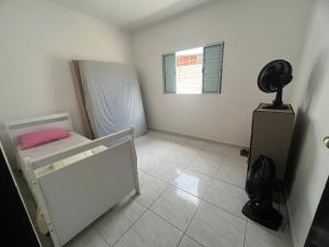 a small bedroom with a bed and a fan at Casinha do refúgio in Mongaguá