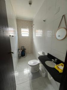 a white bathroom with a toilet and a sink at Casinha do refúgio in Mongaguá