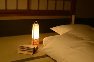 een bed met een lamp en een stapel boeken bij Mitsuki Kyoto in Kyoto